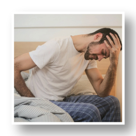Man sitting on on bed with a headache